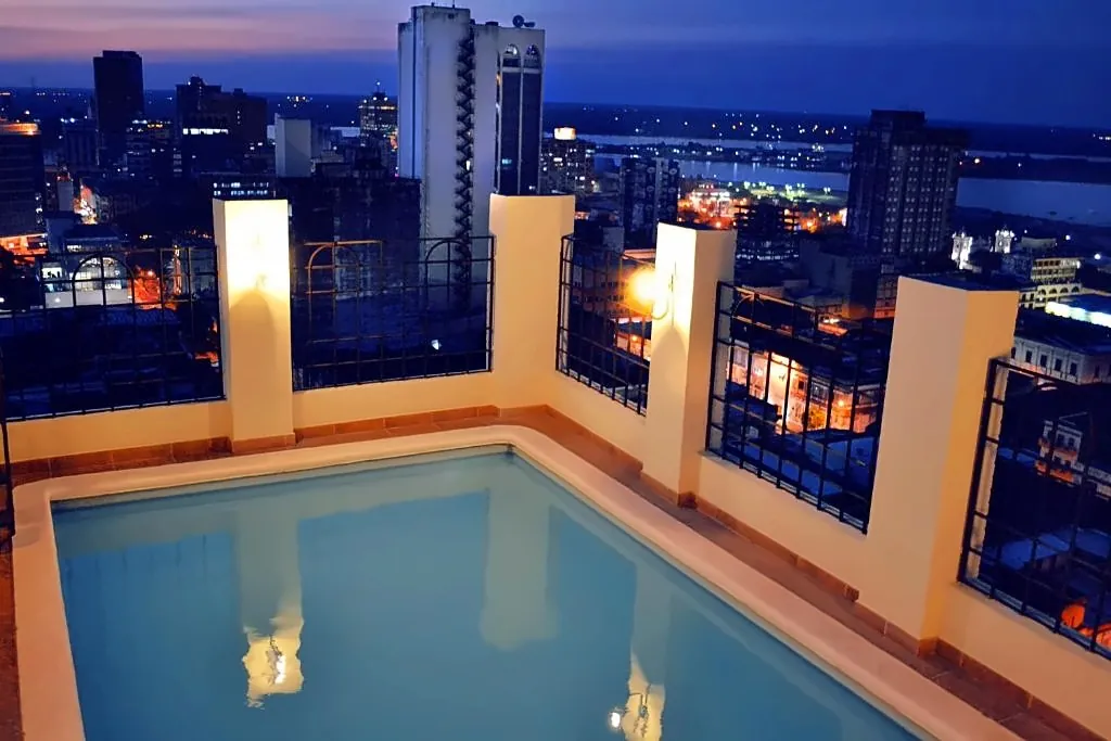 Piscina en la azotea del Manduara Hotel con vista nocturna de Asunción